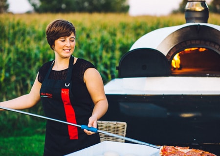 Le Pizzaiolo sort du four une pizza préparée sur place