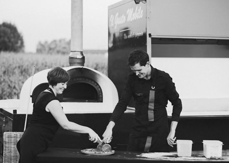 De pizzabakkers versnijden de vers gebakken pizza in stukken.